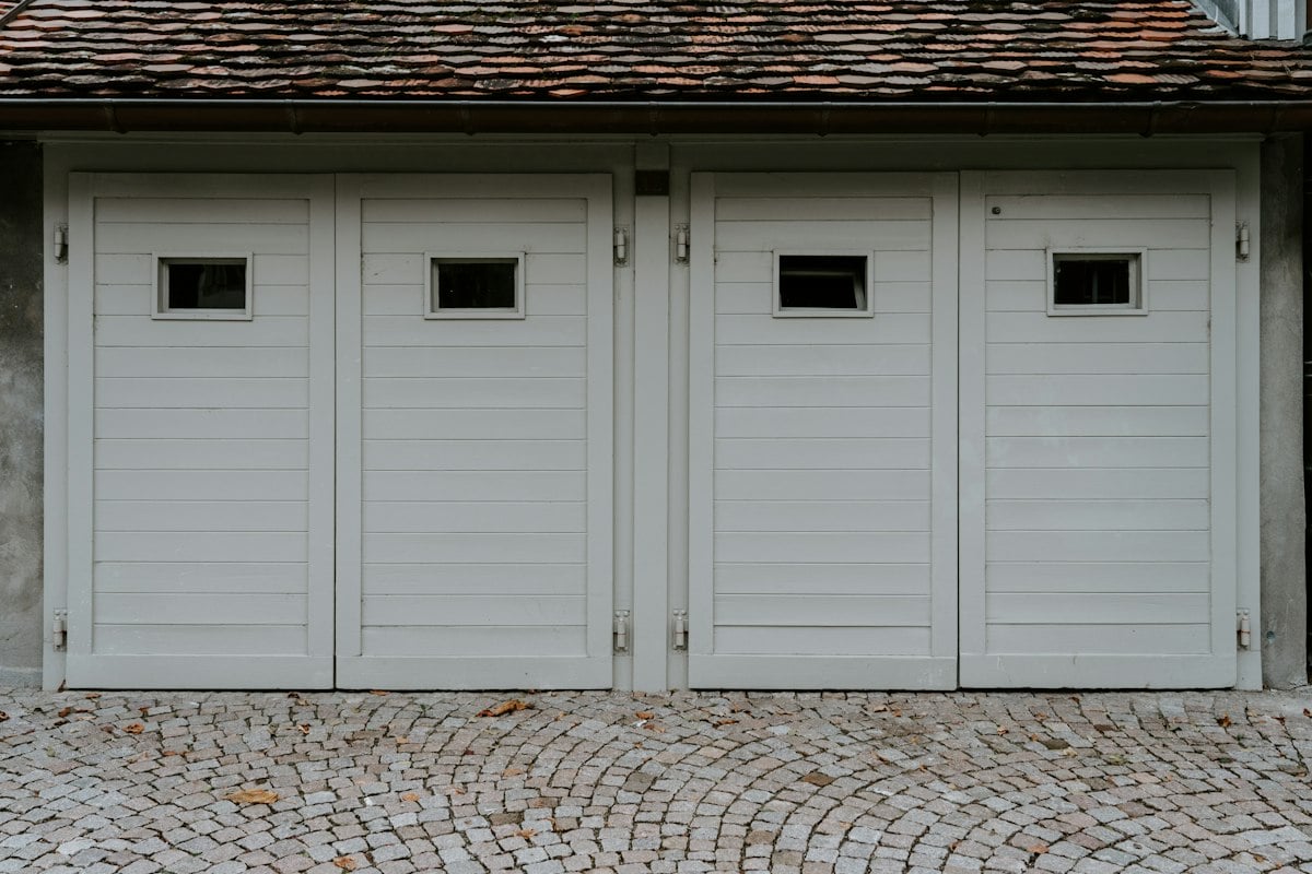Row of white wooden garage doors with small windows