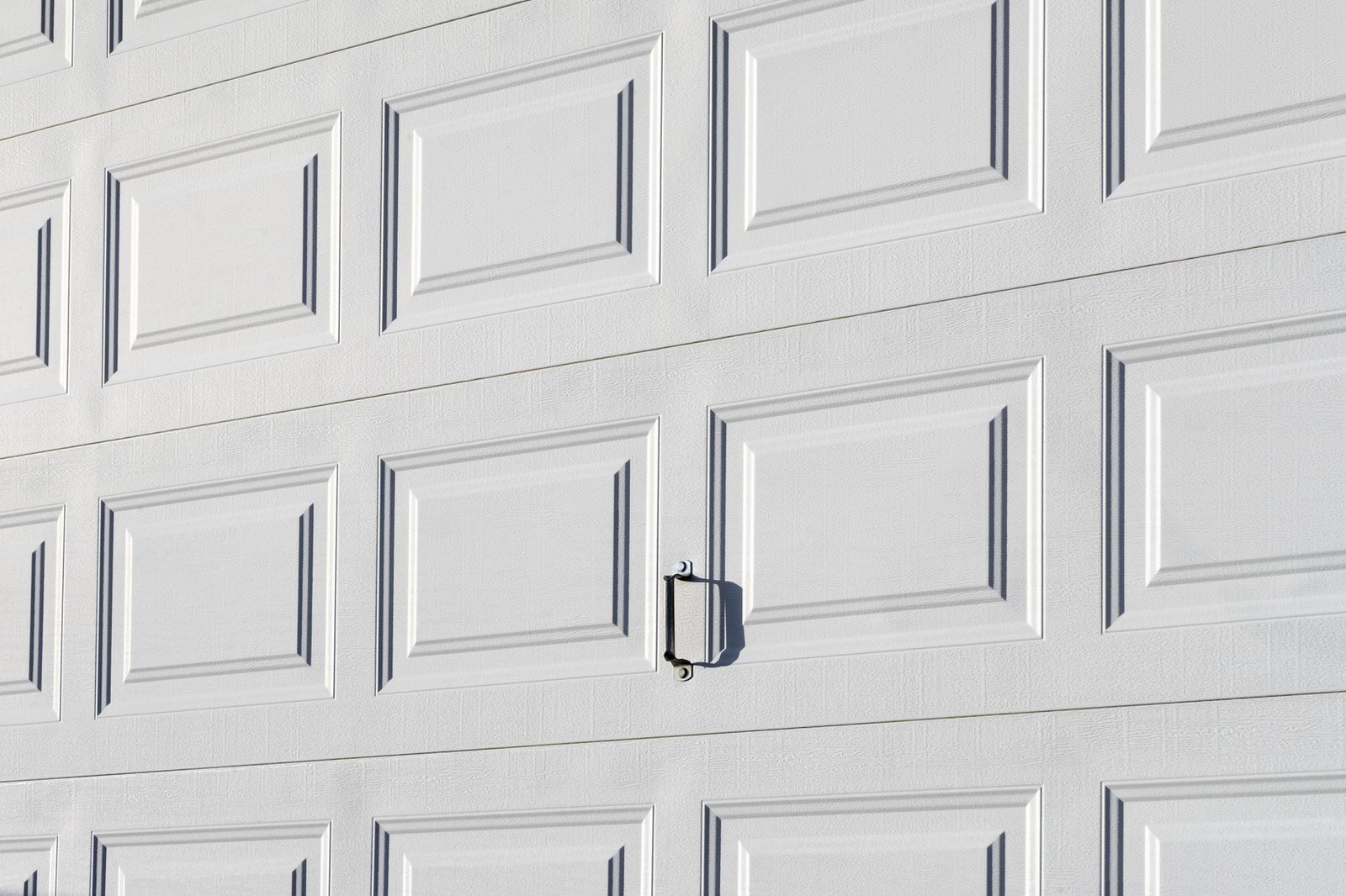 Close view of a white raised-panel garage door and handle